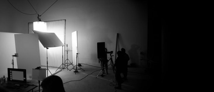 Shooting studio for photographer and creative art director with production crew team setting up lighting flash and LED headlight on tripod and professional equipment for portrait model photo shoot and video online filming